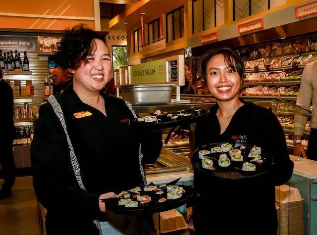 Staff serving sushi samples at the grand opening