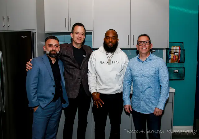 Four members posing in the Kali Audio kitchen area