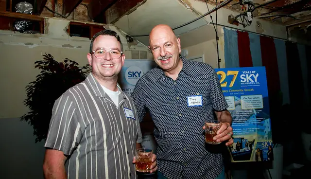 Members networking beside the 27 Years of Sky display